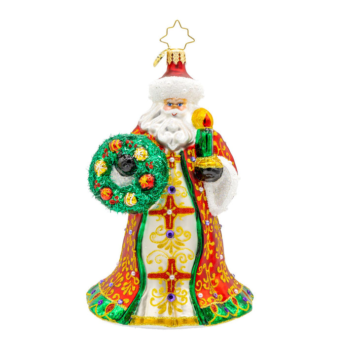 This stunning ornament showcases Santa in a resplendent red and gold robe, hand-painted with intricate designs and finished with shimmering trim. Carrying a glowing green candle and a wreath adorned with shiny holly and colorful ornaments. View of front.