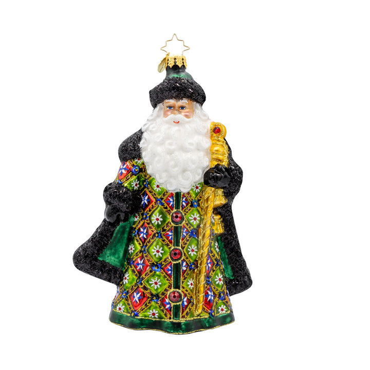 The Opulent Noel ornament. Santa is dressed in a vibrant green satin coat covered in a playful patchwork of colors and glittery designs. With his shiny gold staff, sparkling red gems, and fluffy tinsel fur trim. View of front. 