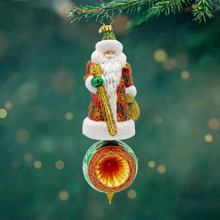 Regal Reflections Ornament. Santa, dressed in his finest attire, stands tall and proud, surrounded by a delightful array of festive motifs. View of front.